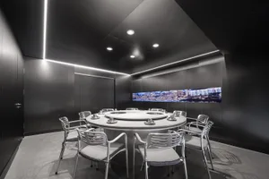 A modern conference room with a round table, black walls, and two TV screens, creating a sophisticated and inviting atmosphere for business meetings