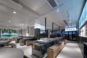 Modern restaurant interior with a large kitchen area, multiple sinks, and dining tables, featuring a functional and efficient design