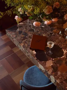 A sophisticated dining area with a marble table, vases, wine glasses, a book, and a cup, suggesting a high-end restaurant or private residence