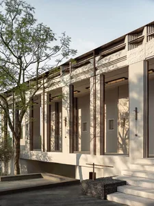 A modern building with a white exterior and varied window shapes and sizes, set against a natural backdrop of trees