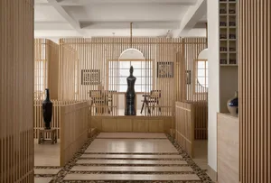 A modern interior design showroom with a large wooden floor, seating options, vases, and decorative elements, creating a warm and inviting atmosphere