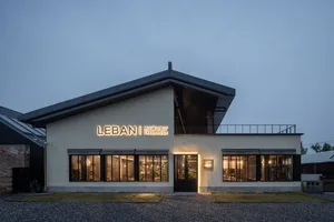 A modern building with a concrete facade, large windows, and a sign reading Lebani, set against a clear blue sky