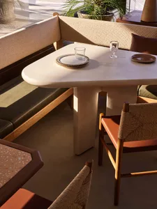 A modern dining area with a large white table surrounded by multiple chairs, set up for a meal in a clean and inviting environment