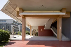 A modern interior space with a red wall, a staircase, and two benches, featuring a spacious atmosphere