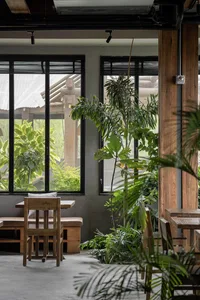 A modern restaurant interior with wooden tables and chairs, multiple dining tables, and benches, creating a warm and inviting atmosphere