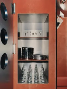 A dimly lit wooden cabinet with bottles and bowls stored on shelves