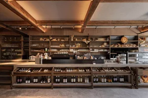 一間井然有序的葡萄酒商店，展示架上陳列各式酒瓶與杯具，為顧客營造溫馨邀約的氛圍
