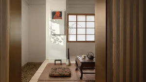 Cozy living space with hardwood floor, white walls, two couches, a chair, a vase, and a bowl, with a warm and inviting atmosphere