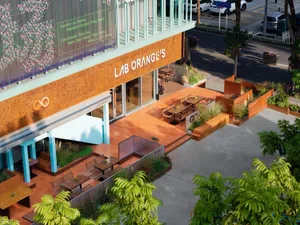 A colorful storefront with a large window and outdoor seating area with chairs in various positions