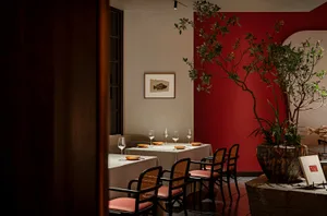 Dining area with a red accent wall, a table, chairs, and wine glasses, creating a sophisticated and inviting atmosphere