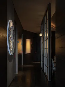 A dimly lit hallway with a wooden floor, two chairs, and a clock on the wall, creating a cozy and mysterious atmosphere