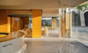 Cozy home interior with a yellow accent wall, glass door, and dining table surrounded by chairs, with a car parked outside