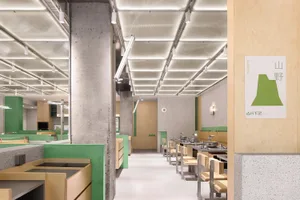 Modern restaurant interior with a green wall, white ceiling, and multiple dining tables and chairs