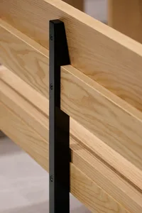 A modern wooden bed with a black metal headboard, featuring a sleek and minimalist design with high-quality wood and a warm inviting feel