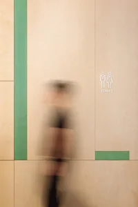 一名男子走在綠牆辦公室走廊，對側為白牆，設有兩個標誌牌，展現專業氛圍