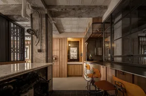 Warm and inviting open kitchen with wooden floors and walls, featuring a dining table, chairs, sink, and refrigerator