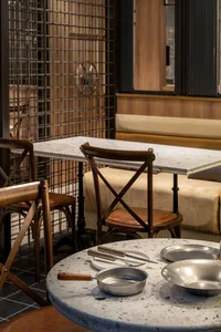 A modern restaurant interior with wooden tables and chairs, featuring multiple dining tables and chairs in a warm and inviting atmosphere