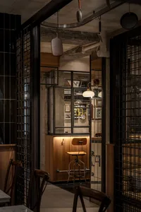 燈光柔和的休閒餐廳區，配有餐桌與椅子，周圍環繞磁磚牆，背景有其他餐桌