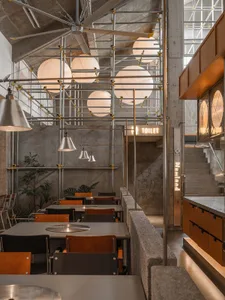A modern restaurant with a large dining area featuring several tables and chairs, creating an inviting atmosphere for socializing and meals