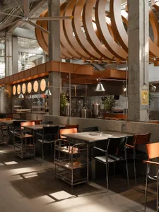 Industrial kitchen with a modern dining area, featuring a large dining table, appliances, and potted plants, in a clean and organized space
