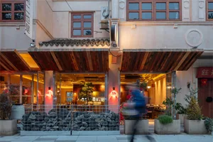 Casual restaurant interior with stone exterior, wooden furniture, and potted plants