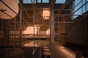 Industrial restaurant space with concrete walls, multiple dining tables, and dim lighting