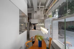 Open kitchen with white walls, wooden floors, a dining table, chairs, and kitchen appliances