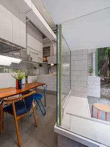 Bright and inviting kitchen with a dining table, chairs, sink, oven, refrigerator, and potted plants, illuminated by natural light
