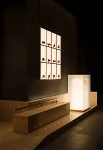 A darkened room with multiple rows of red hearts arranged vertically on the wall in varying sizes and positions, creating a striking visual effect