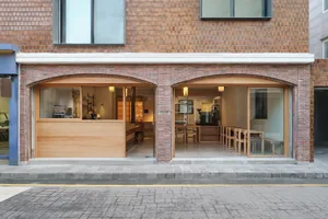 Open restaurant interior with brick walls, wooden floors, and well-lit dining areas with tables and chairs
