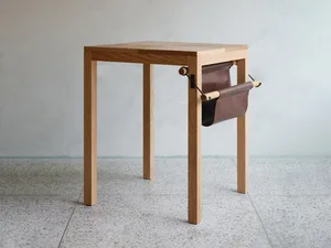 A minimalist wooden table with a leather strap across its surface, set against a neutral background
