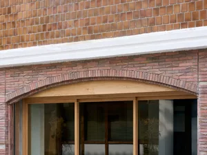 A rendered image of a brown brick building with a window on one side, set against a neutral background