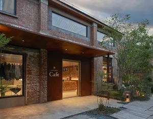 A brick building with large windows, providing natural light and a cozy atmosphere for a cafe
