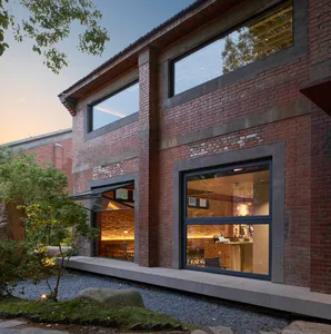 A rendered image of a brick building with a large window and a cozy patio area with chairs, suggesting a warm and inviting interior space