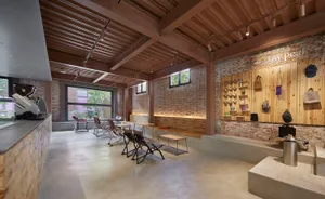 Cozy living area with a brick building, a dining table, potted plants, and scattered bottles, creating a warm and inviting atmosphere