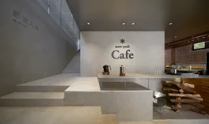 Modern cafe interior with concrete walls, minimalist decor, and seating areas with tables and chairs, featuring a vase and cups