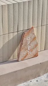 An outdoor entrance with a marble rock and a brick wall in the background