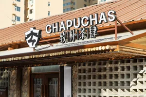 Cozy Asian restaurant with a wooden exterior, tables, chairs, and a sign reading Chapuchas