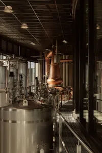 Industrial workspace with stainless steel equipment, pipes, and multiple tanks in a processing or storage area