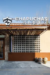 A restaurant building with a brown facade, adorned with many windows, and two large vases in front, creating a warm and inviting atmosphere