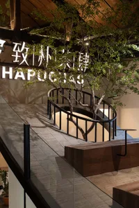 A staircase with a wooden bench, black railing, and two trees in the background, creating a calm and inviting atmosphere
