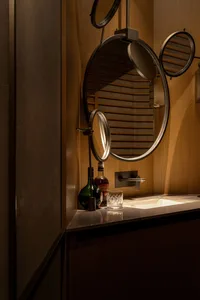 Bathroom with a sink, mirror, and wine bottle, featuring an elegant and sophisticated atmosphere