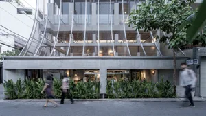 A bustling street scene with a modern building featuring a large glass wall, surrounded by people walking by