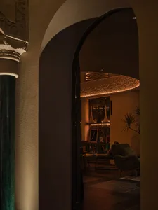 Cozy living space with an archway, two chairs, a potted plant, and a sense of depth and connection to another room