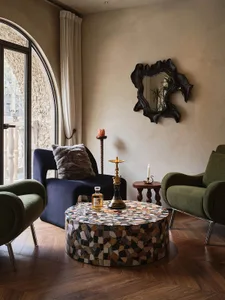 Cozy living space with brick walls, two green chairs, a coffee table, and a potted plant, with a warm and inviting atmosphere