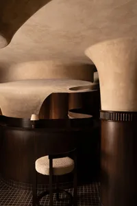 A round room with wooden panel walls, a spiral staircase, a chair, and a couch, creating a modern and cozy atmosphere