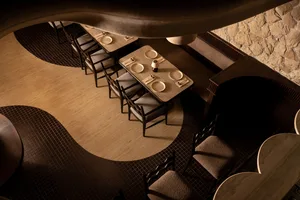 Sophisticated dining space with multiple tables, chairs, and a mix of wood and tile flooring, featuring a vase on one of the tables