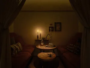 Cozy living space with two couches, chairs, and a dining table, surrounded by red walls and well-lit by natural and artificial light sources