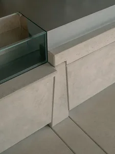 A modern kitchen countertop made of concrete with a glass window and a sink, set against a blank background