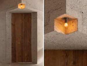 Interior space with wooden doors in a cement wall and a doorway with a stone wall, featuring a yellow hanging light bulb for warmth and modern style